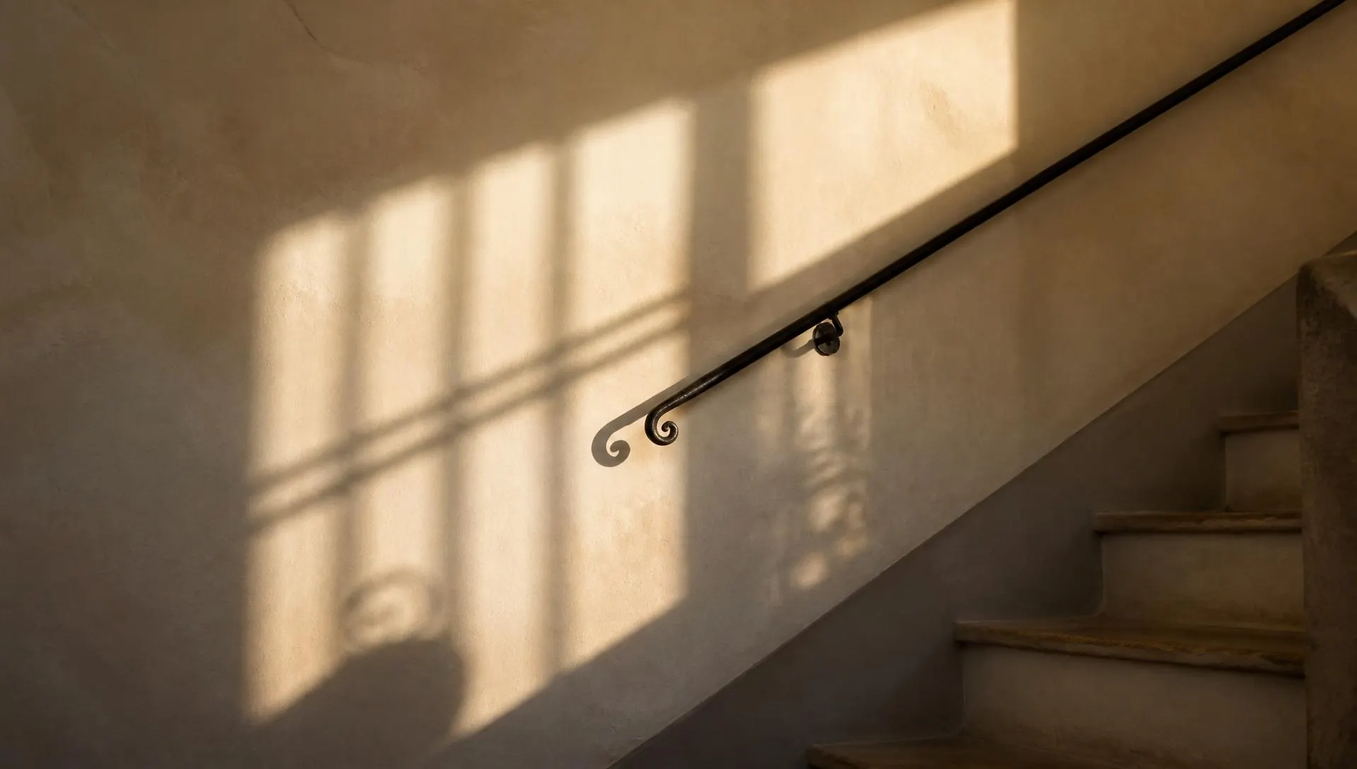 Light and stair rail shadows across a warm stairwell wall, therapy for first generation professionals in Virginia